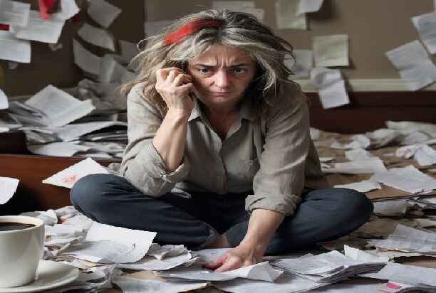 Discouragement on the face of a woman surrounded by a mess of papers that's lacking Contentment.