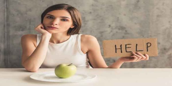 woman at dinner table and her plate only has one apple on it end eating disorders