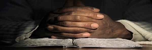 Praying hands on open Bible