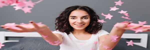 Woman releasing paper stars symbolizing how you should Reach for Your Dreams with Self-Improvement Prayers 