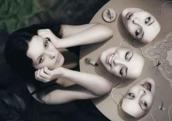 A woman sitting at a table with masks, deeply reflecting on her identity and beliefs.